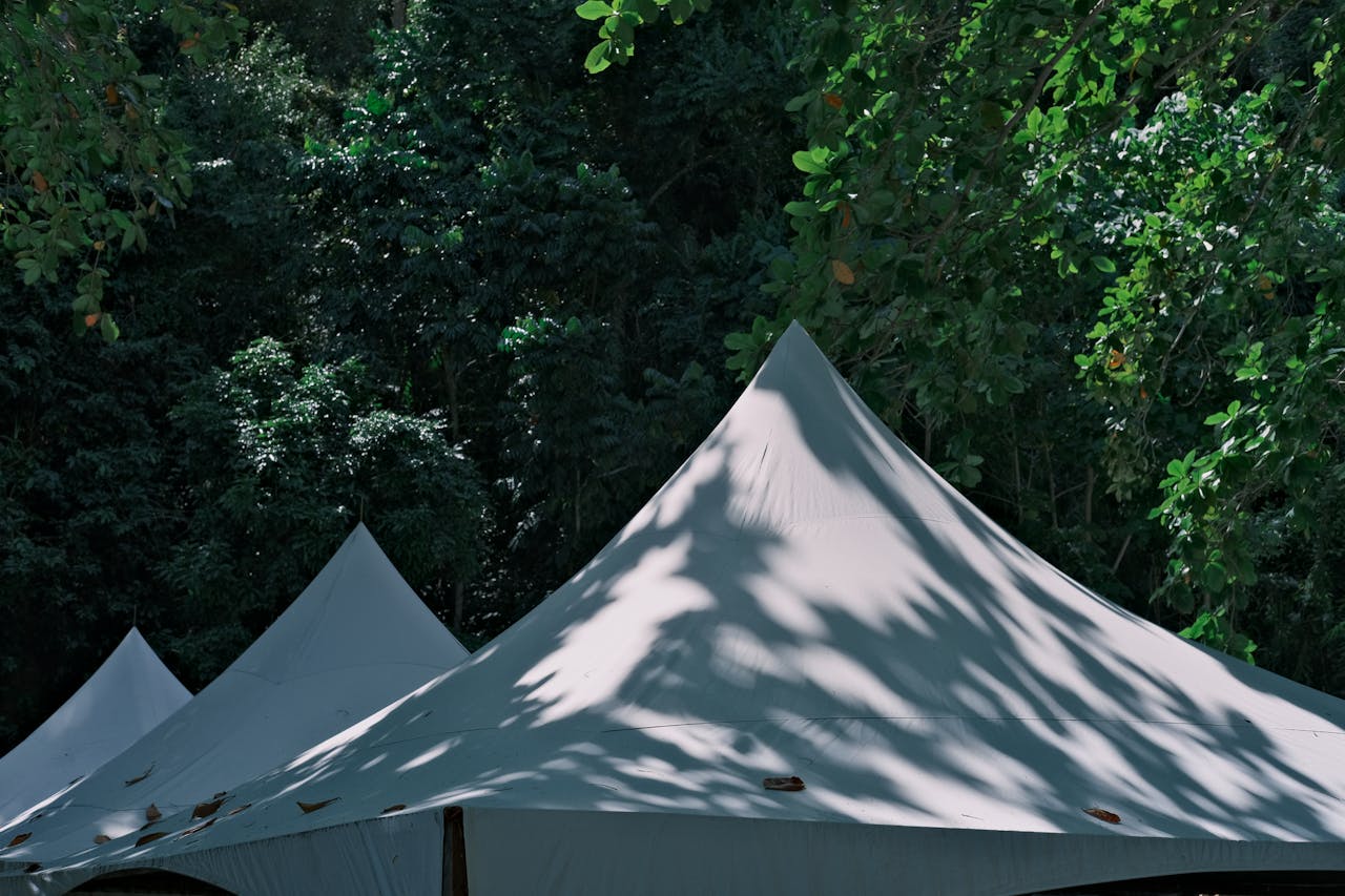 Elegant white tents surrounded by vibrant greenery in a serene outdoor setting.